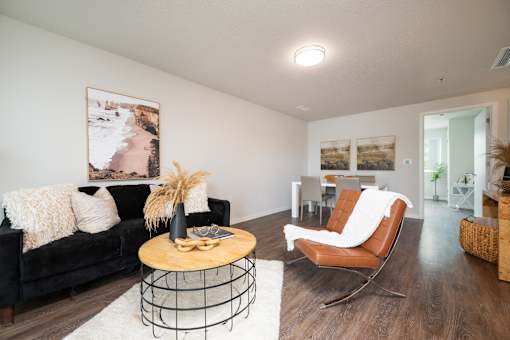 A living room with a black couch, a wooden coffee table, and a chair.
