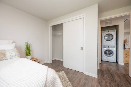 A white bedroom with a washer and dryer in the closet.