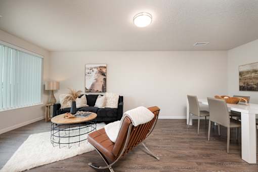 A living room with a black couch, a wooden rocking chair, and a white dining table.