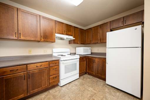 A kitchen with white appliances and wooden cabinets.