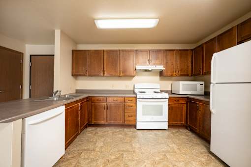 A kitchen with white appliances and brown cabinets.