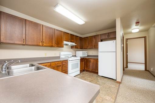 A kitchen with white appliances and wooden cabinets.