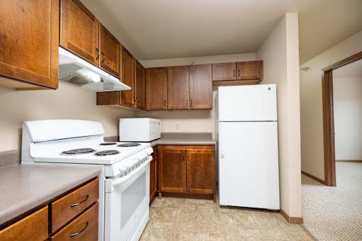 A kitchen with white appliances and wooden cabinets.