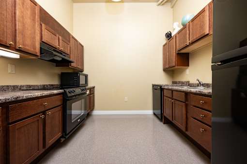 A kitchen with wooden cabinets and black appliances.