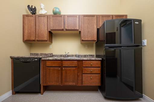 A kitchen with a black fridge and a black dishwasher.