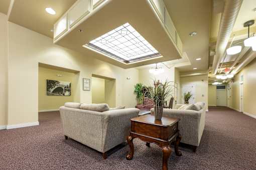 A living room with a couch, a table, and a skylight.