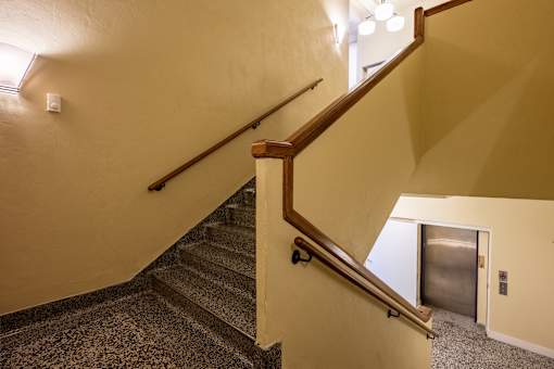 A staircase with a wooden handrail and a metal handrail.