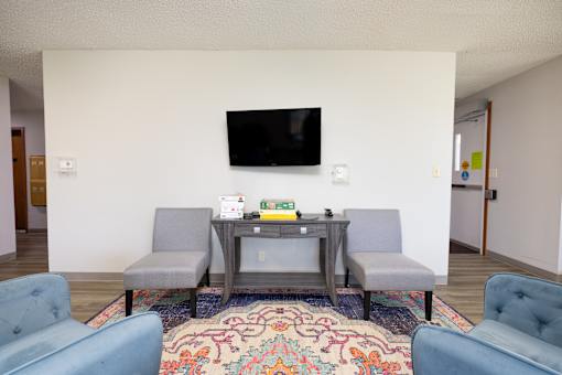 A living room with a grey sofa and a television mounted on the wall.