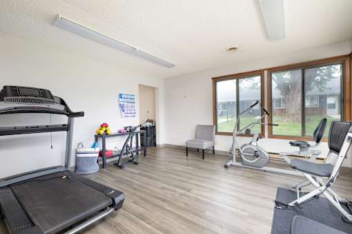 A home gym with a treadmill, exercise bike, and other equipment.