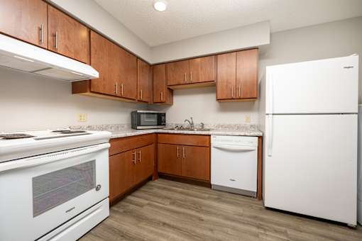 A kitchen with white appliances and wooden cabinets.