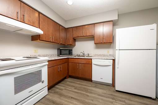 A kitchen with white appliances and wooden cabinets.