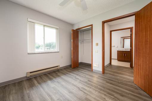 A room with wooden floors and a window with blinds.