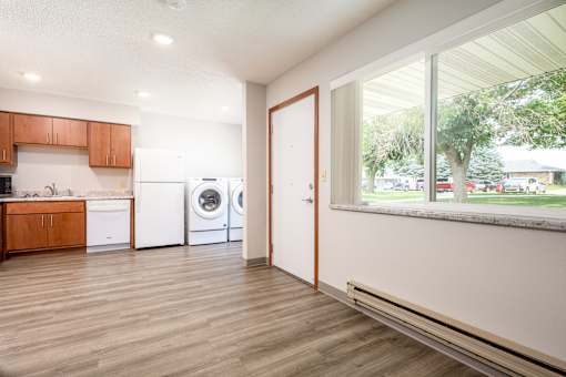 A modern kitchen with wooden floors and white appliances.