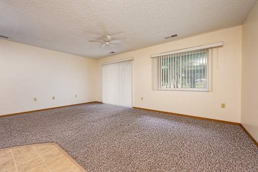 A room with a carpeted floor and a ceiling fan.