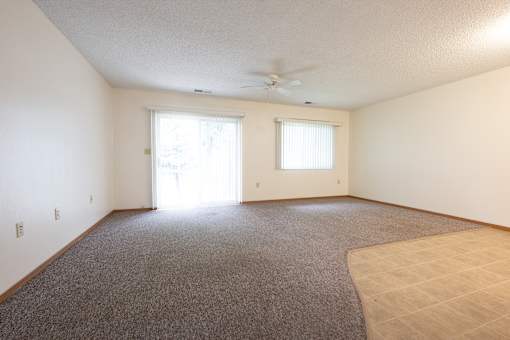 A room with a carpeted floor and a ceiling fan.