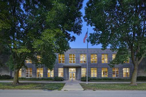A building with a flag on top and trees in front.