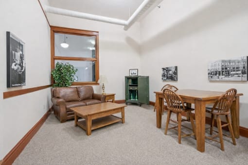A living room with a brown couch, wooden coffee table, and a dining table with chairs.