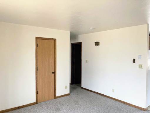 an empty living room with a door and white walls
