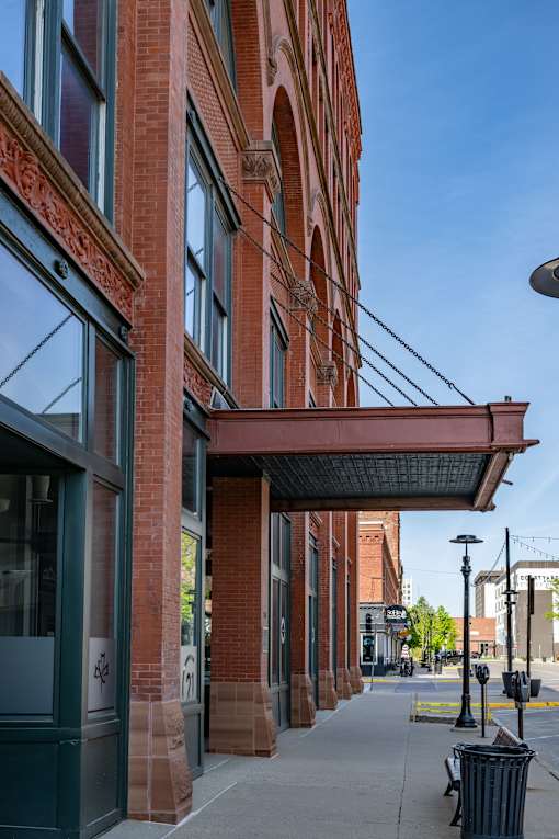 A red brick building with a black trash can in front of it.