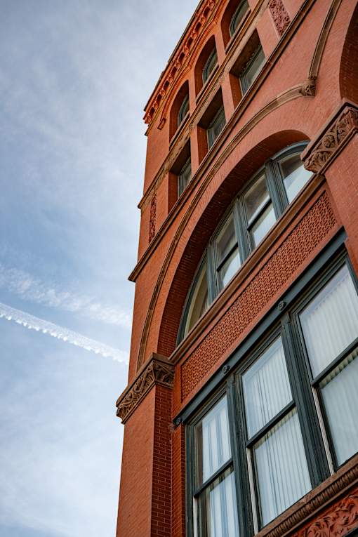 A tall red brick building with ornate window frames.