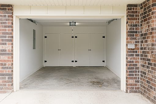 A garage with a white door and brick walls.