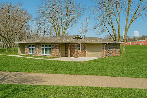 A house with a brown roof and a green lawn in front.
