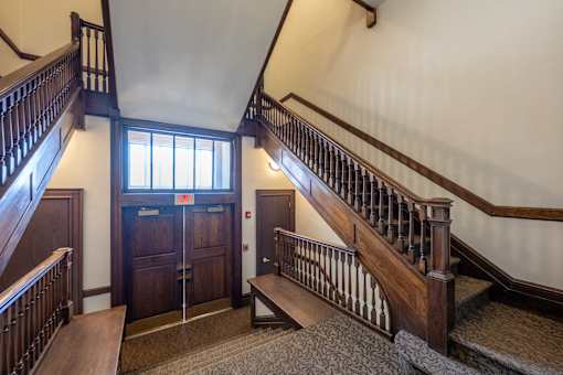 A staircase with a wooden handrail and a carpeted floor.