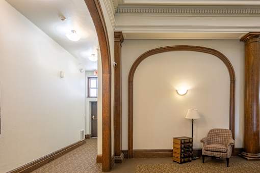 A room with a brown carpet and a lamp on a side table.