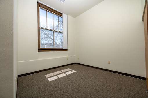 A room with a window and a carpet with a white square on it.