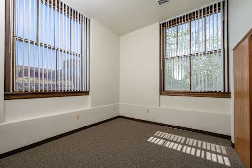 A room with two windows and a carpeted floor.