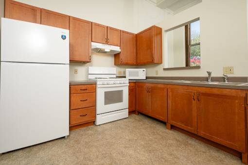 A kitchen with brown cabinets and white appliances.