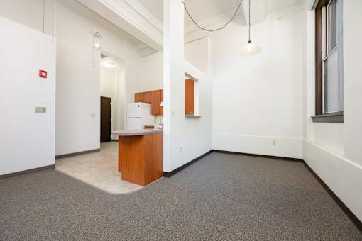 A white room with a brown desk and a white fridge.