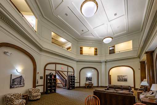 A large room with a couch, chairs, and a bookcase.