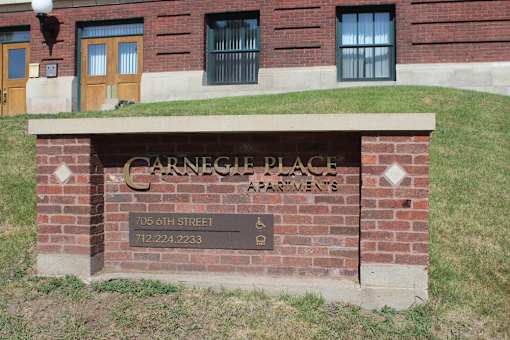A brick wall with a sign that says Carnegie Place Apartments.
