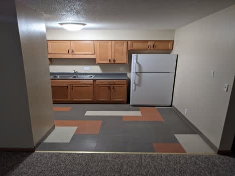 A kitchen with a white refrigerator and wooden cabinets.