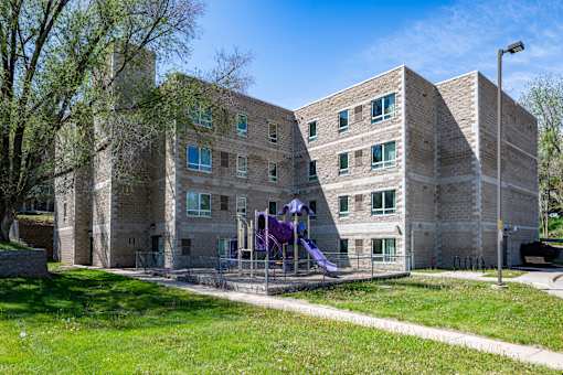 A playground with purple slides is in front of a brick building.