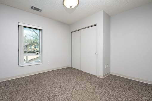 A room with a carpeted floor, a window, and a door.
