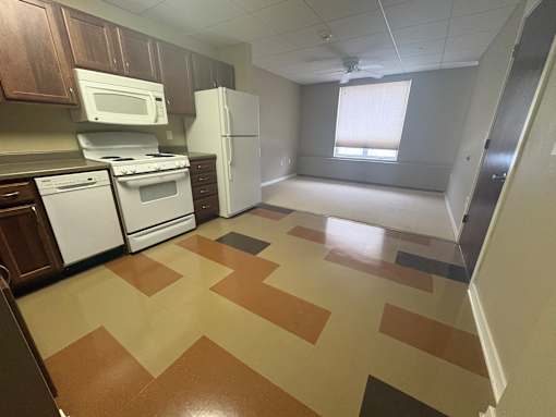 A kitchen with brown and tan tiled flooring.