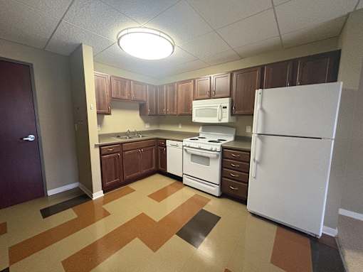 A kitchen with white appliances and brown cabinets.