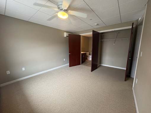 A room with a ceiling fan and carpeted floor.