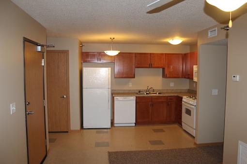 A kitchen with white appliances and wooden cabinets.