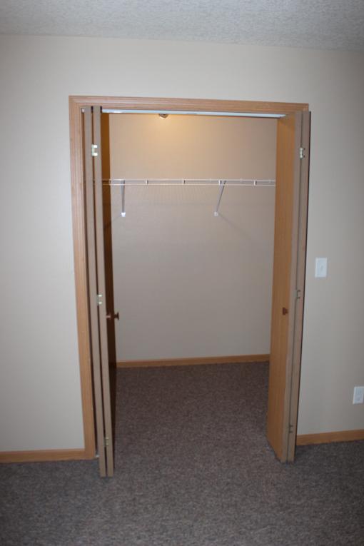 A mirror with a wooden frame is hanging on a wall above a wooden shelf.