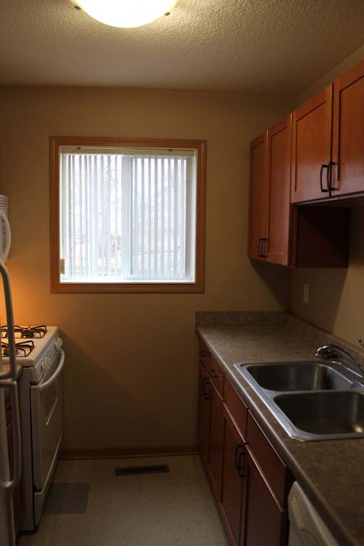 A small room with a window and a microwave above a stove.
