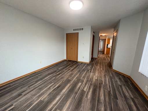 A long hallway with wood floors and a door at the end.