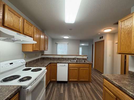 A kitchen with a white stove top oven and a white dishwasher.