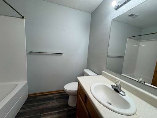 A white sink is on a countertop in a bathroom with a toilet and a bathtub.