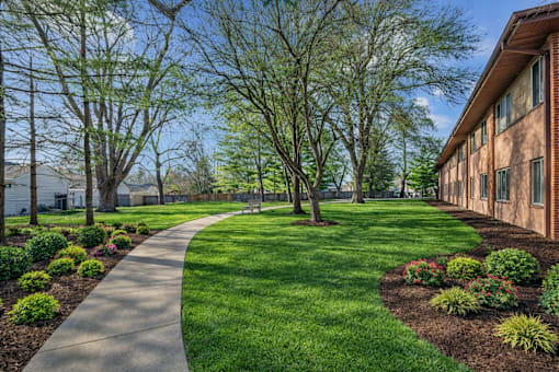 A walkway leads through a grassy area with trees and shrubs.