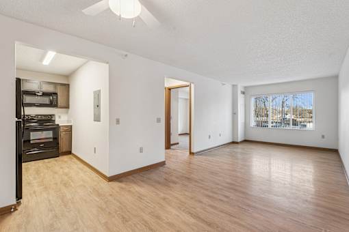 A spacious room with wooden floors and a ceiling fan.