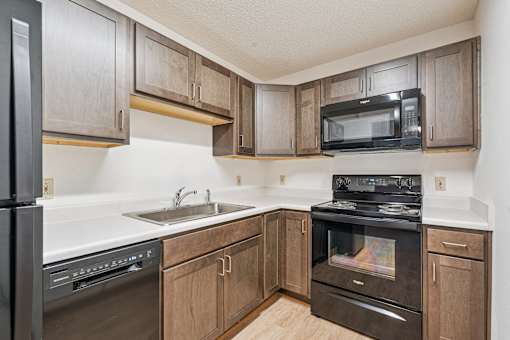 A kitchen with wooden cabinets and black appliances.
