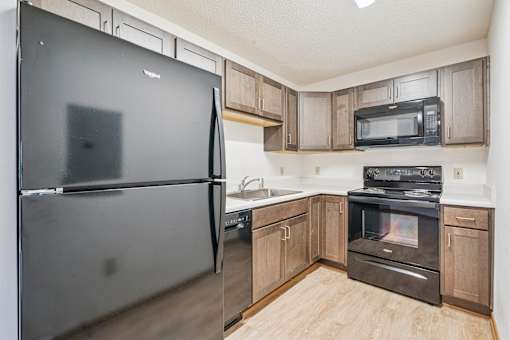 A kitchen with a black refrigerator, black oven, and black microwave.